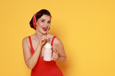 Photo of Pin-up woman in swimsuit with milk shake on orange background, space for text