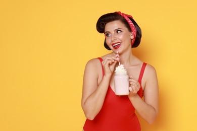 Pin-up woman in swimsuit with milk shake on orange background, space for text