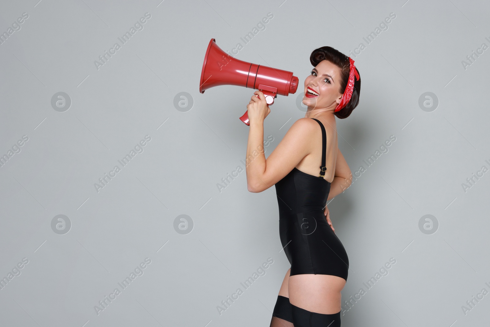 Photo of Pin-up woman with megaphone speaker on grey background, space for text