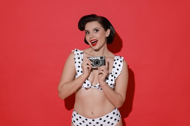 Photo of Pin-up woman in bikini with camera on red background