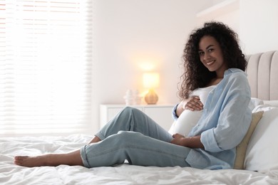 Portrait of beautiful pregnant woman on bed at home