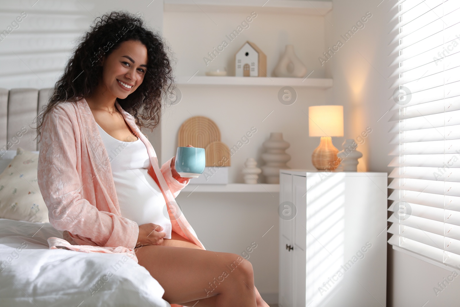 Photo of Portrait of beautiful pregnant with cup of drink on bed at home