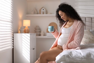 Photo of Portrait of beautiful pregnant with cup of drink on bed at home