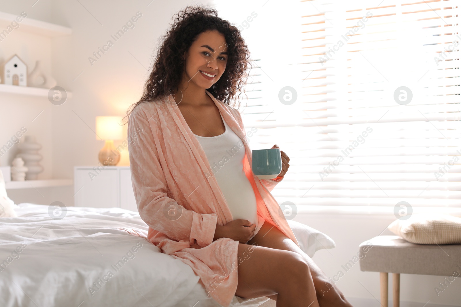 Photo of Portrait of beautiful pregnant with cup of drink on bed at home