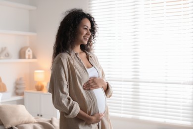 Photo of Portrait of beautiful pregnant woman near window at home, space for text