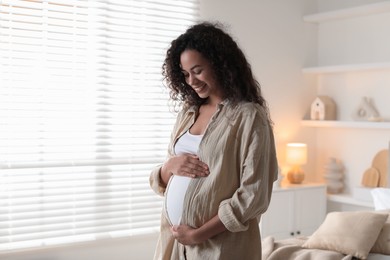 Photo of Portrait of beautiful pregnant woman near window at home, space for text