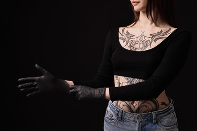 Photo of Professional tattoo artist wearing gloves on black background, closeup