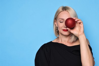 Photo of Woman with Christmas bauble on light blue background. Space for text