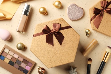 Decorative cosmetics as Christmas present. Makeup products, gift boxes and festive balls on beige background, flat lay