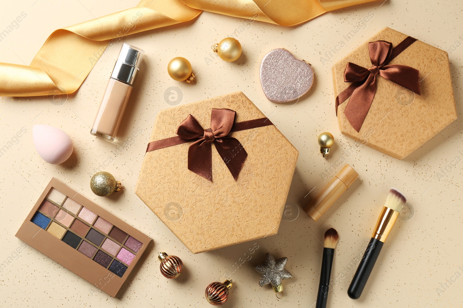 Photo of Decorative cosmetics as Christmas present. Makeup products, gift boxes and festive balls on beige background, flat lay