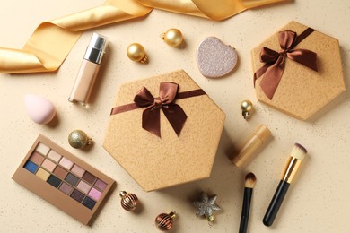 Decorative cosmetics as Christmas present. Makeup products, gift boxes and festive balls on beige background, flat lay