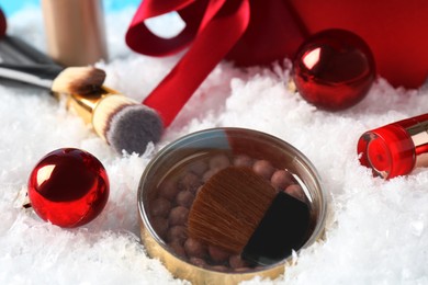 Christmas present. Decorative cosmetics and makeup brushes on snow, closeup