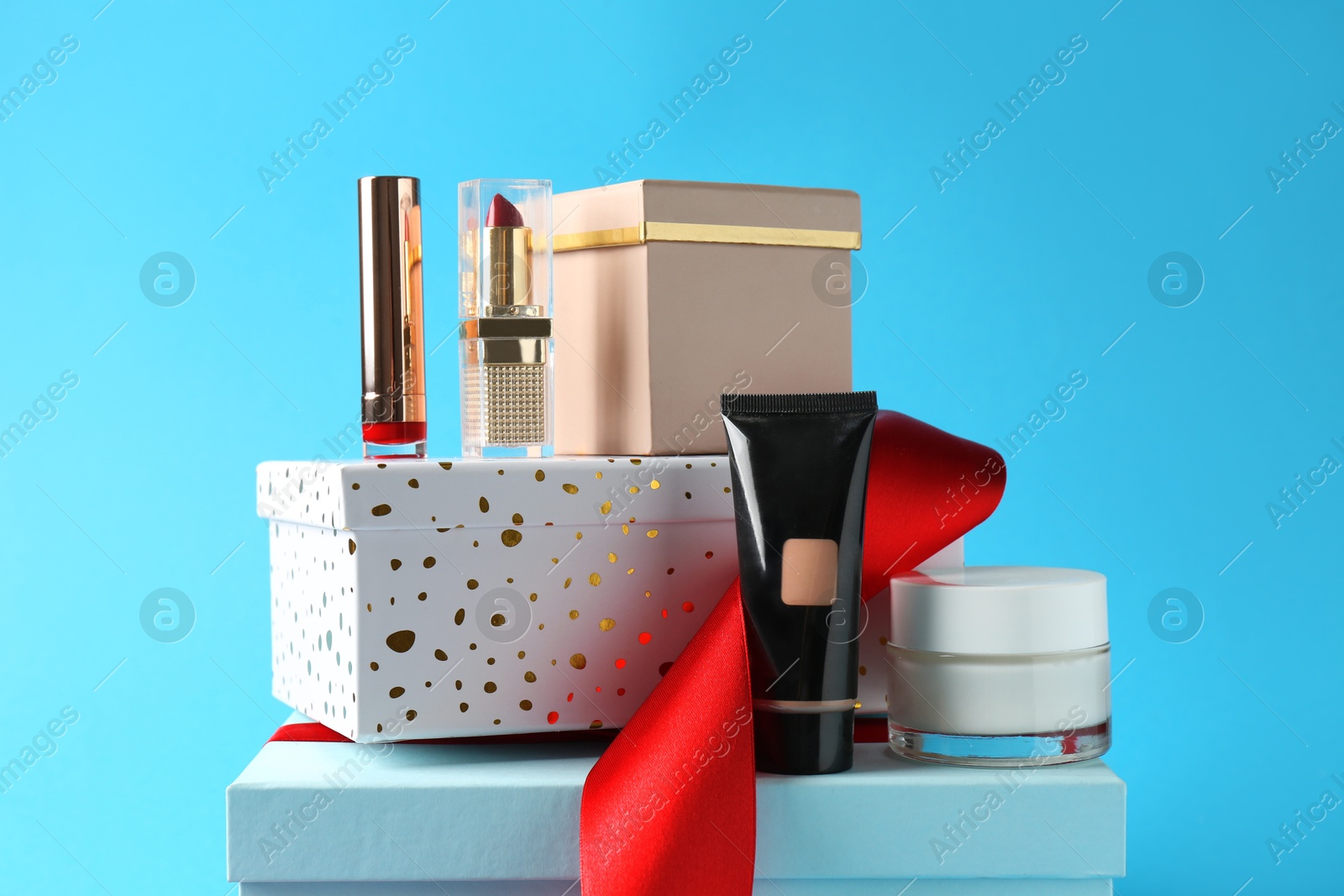 Photo of Christmas present. Decorative cosmetics and gift boxes on light blue background