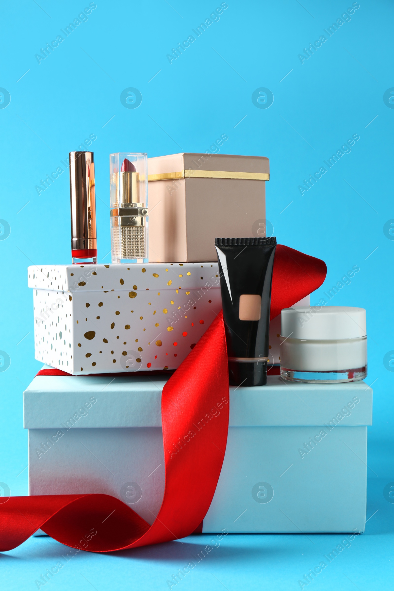 Photo of Christmas present. Decorative cosmetics and gift boxes on light blue background