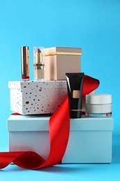 Photo of Christmas present. Decorative cosmetics and gift boxes on light blue background