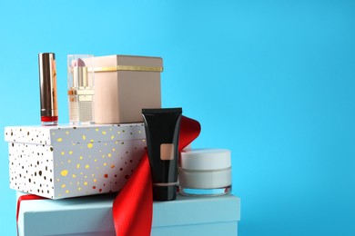 Christmas present. Decorative cosmetics and gift boxes on light blue background. Space for text