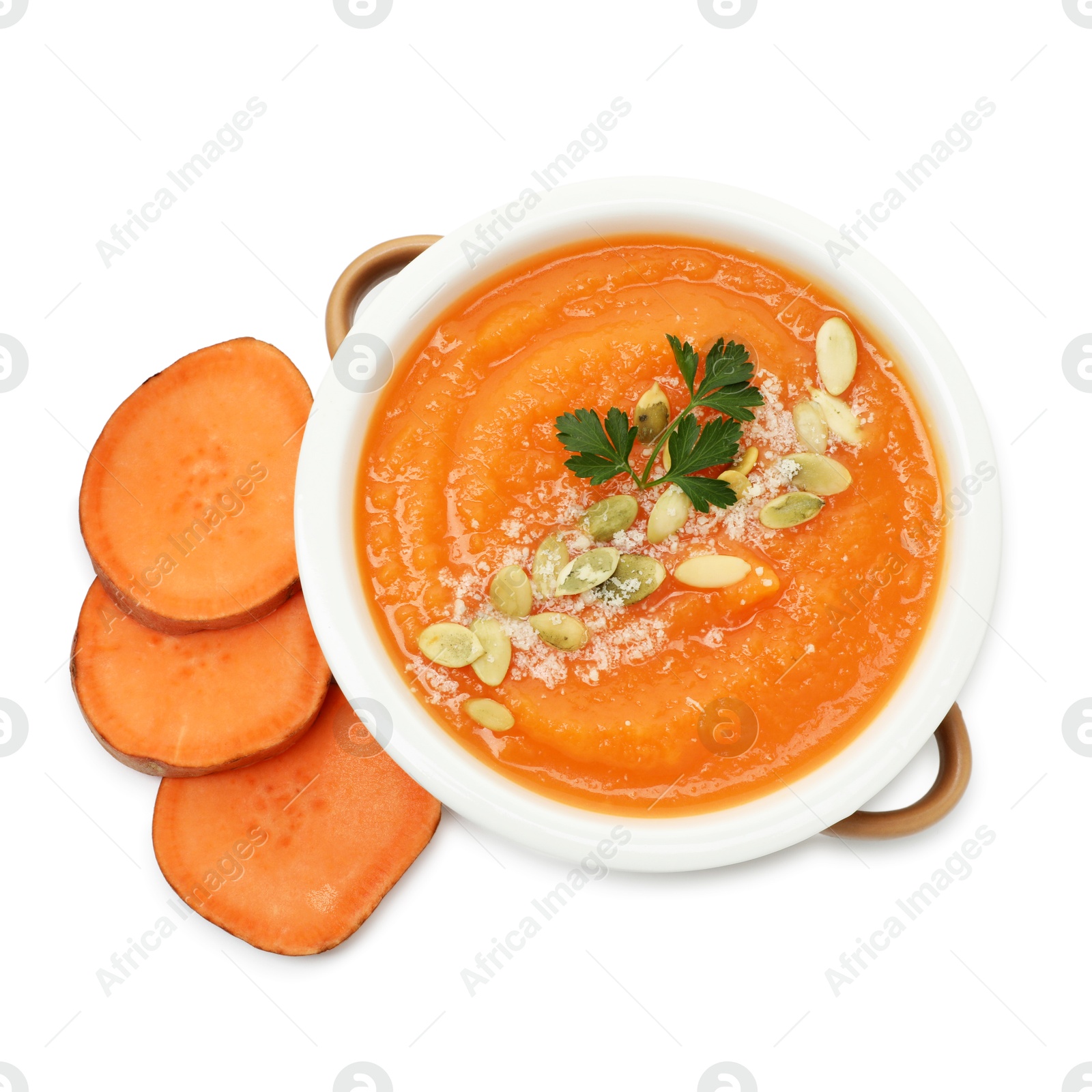 Photo of Delicious sweet potato soup with pumpkin seeds in bowl and fresh vegetable isolated on white, top view