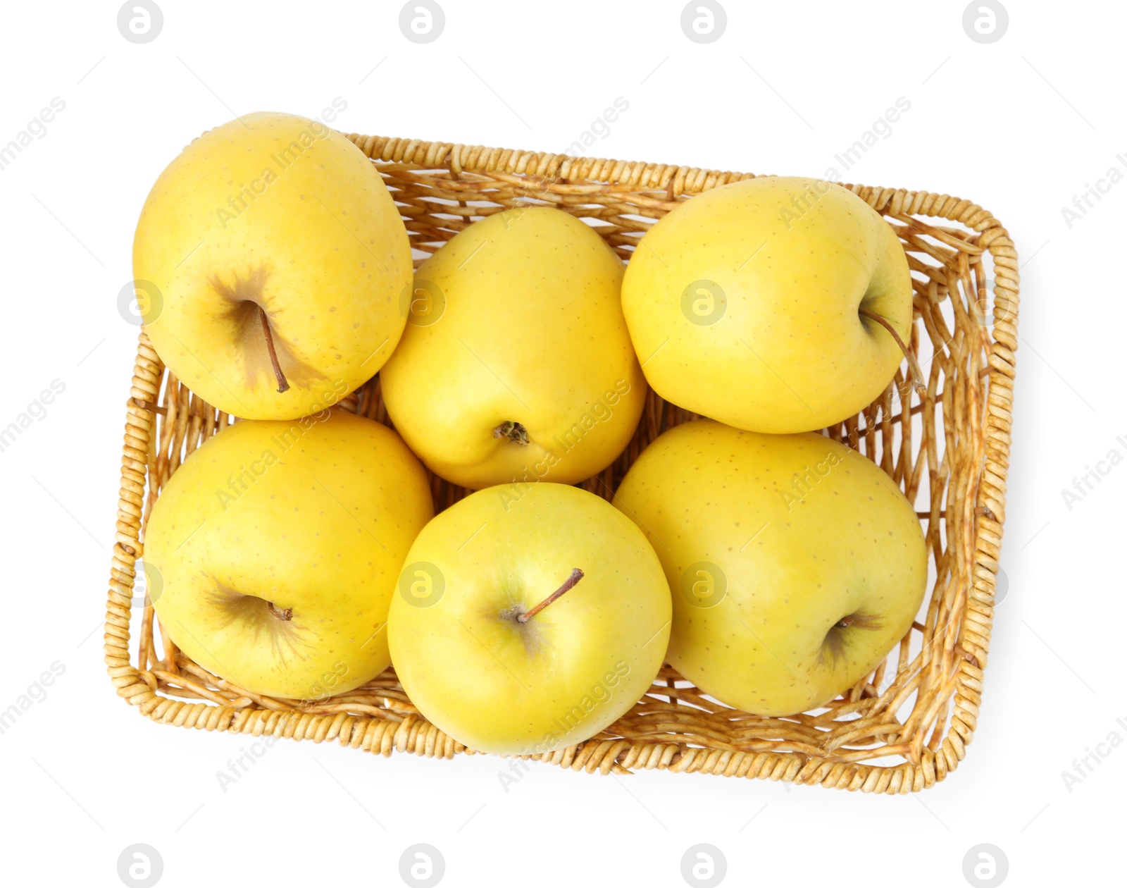 Photo of Many fresh yellow apples in wicker basket isolated on white, top view