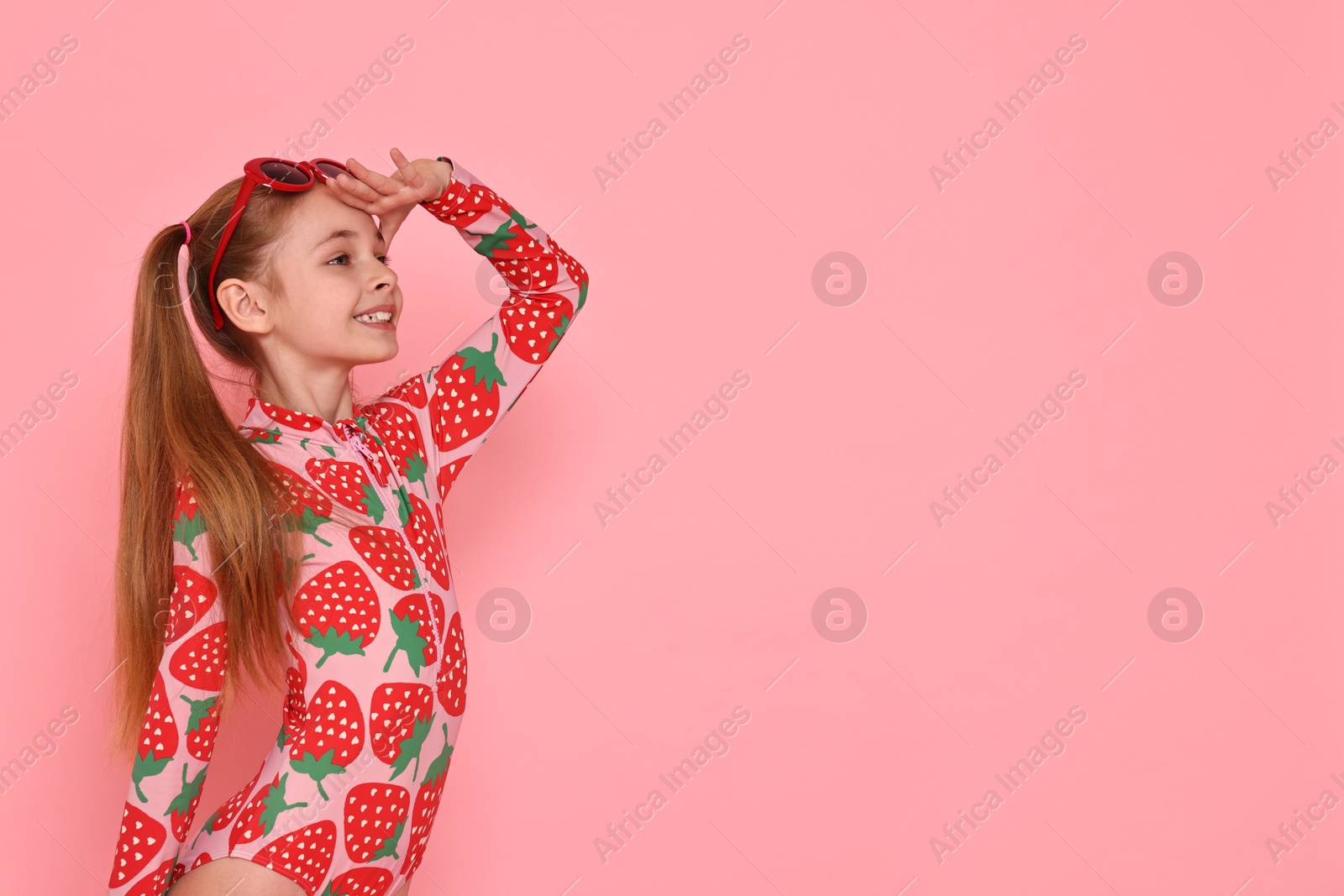 Photo of Happy girl in beachwear and sunglasses on pink background, space for text