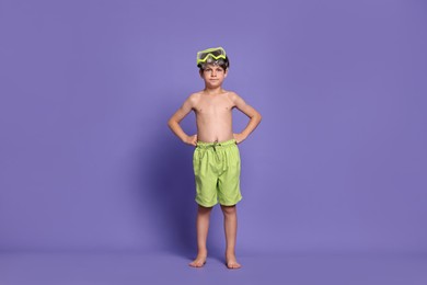 Photo of Little boy in beachwear with diving mask on purple background