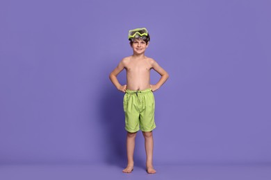 Photo of Little boy in beachwear with diving mask on purple background