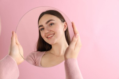 Photo of Woman holding round mirror on pink background, closeup. Space for text