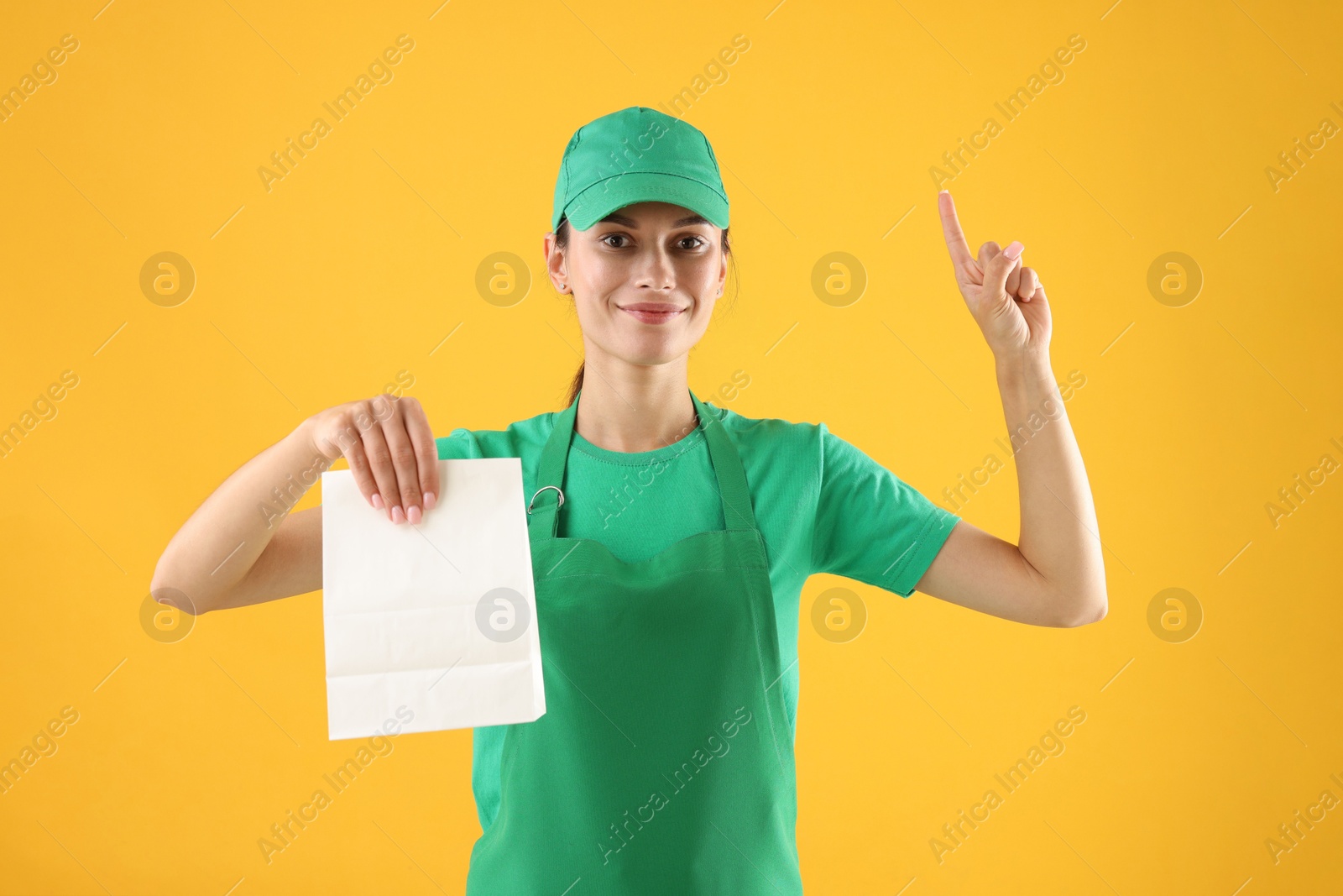 Photo of Fast-food worker with paper bag on orange background