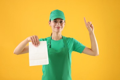 Photo of Fast-food worker with paper bag on orange background