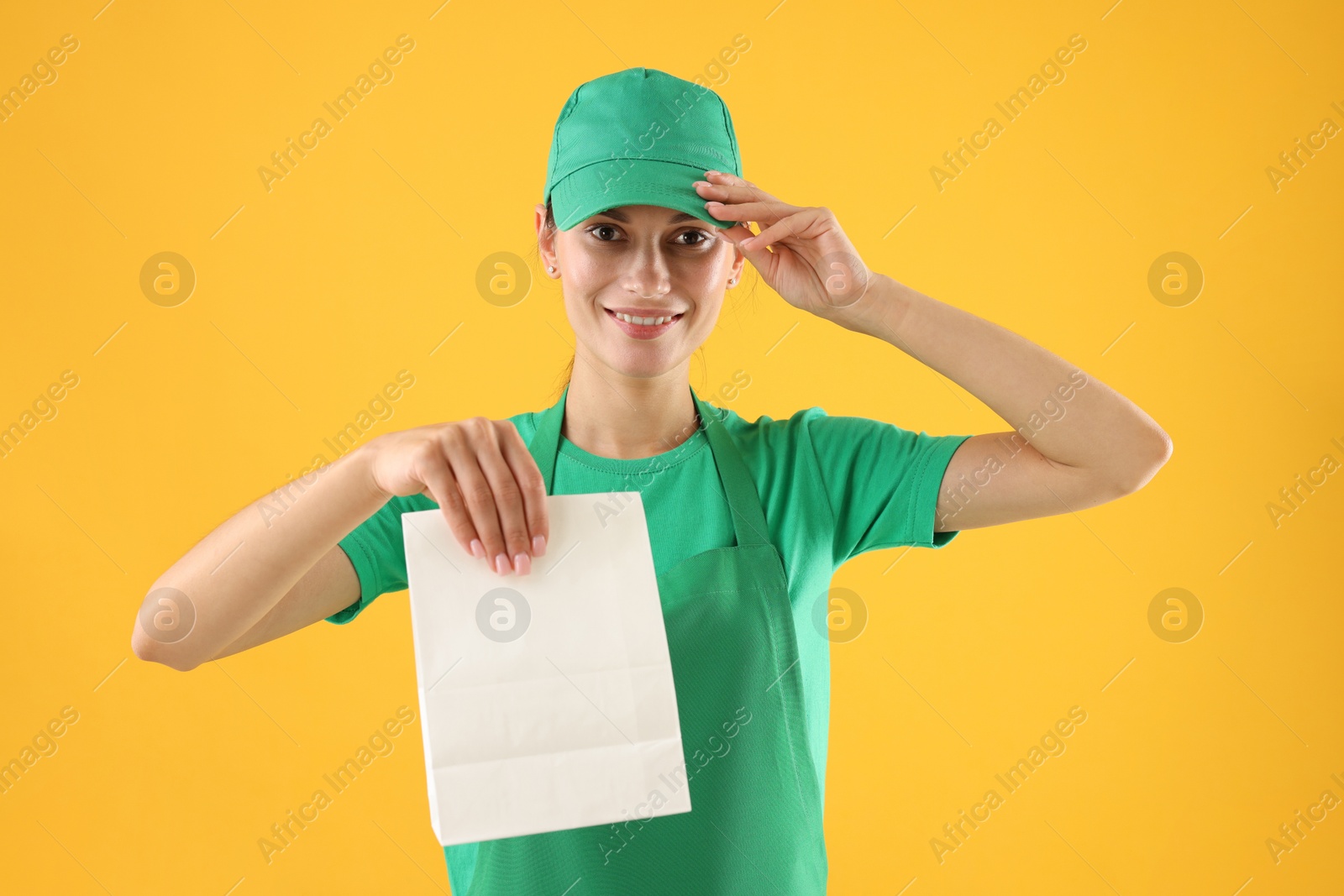 Photo of Fast-food worker with paper bag on orange background