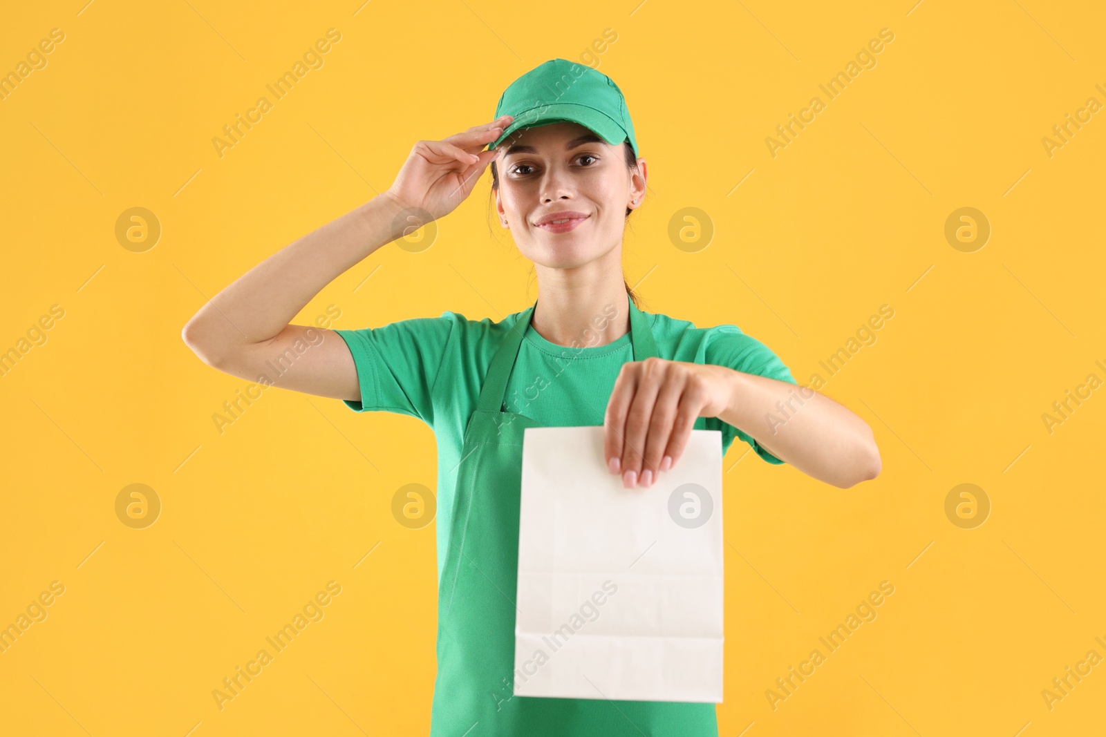 Photo of Fast-food worker with paper bag on orange background