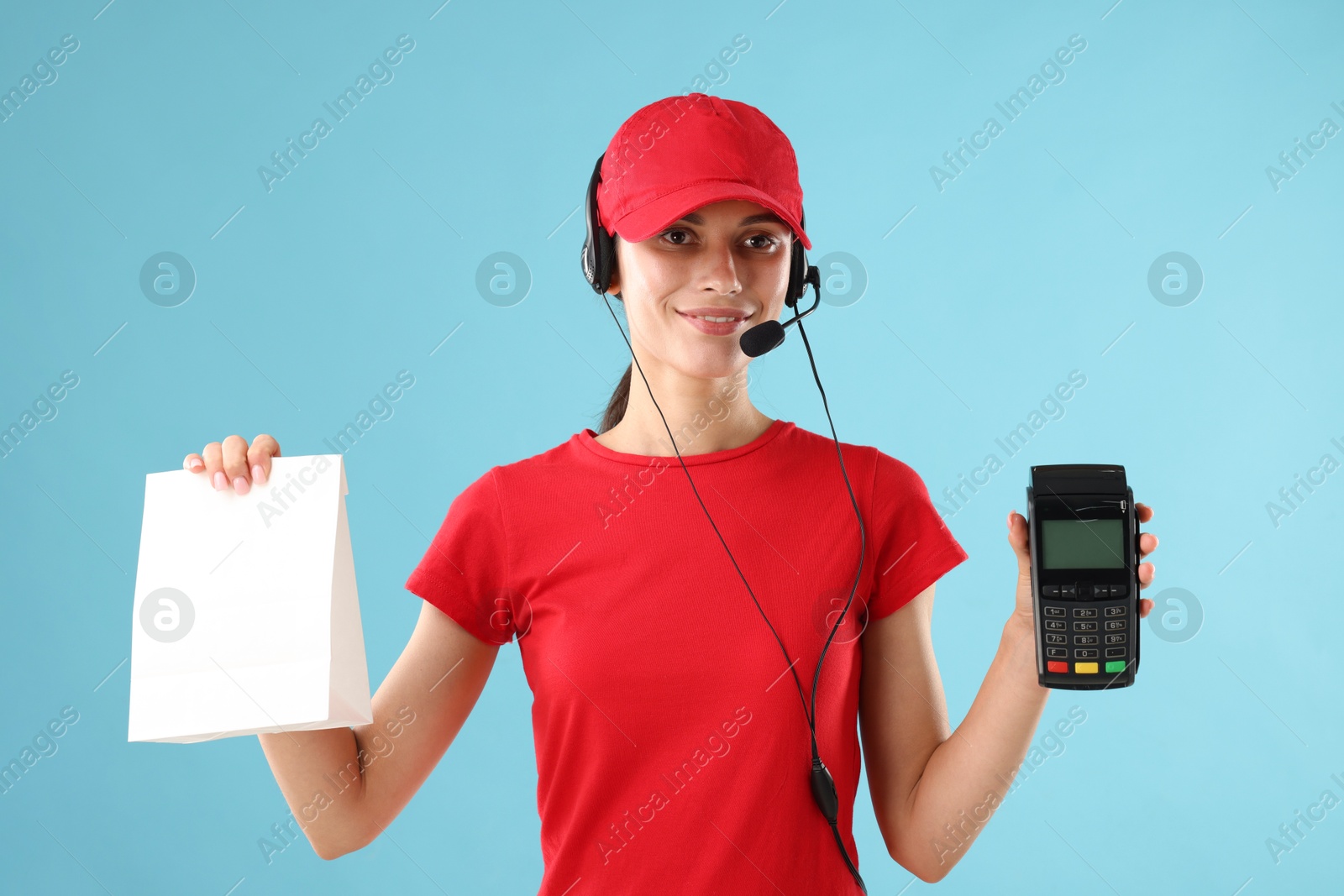 Photo of Fast-food worker with paper bag and payment terminal on light blue background