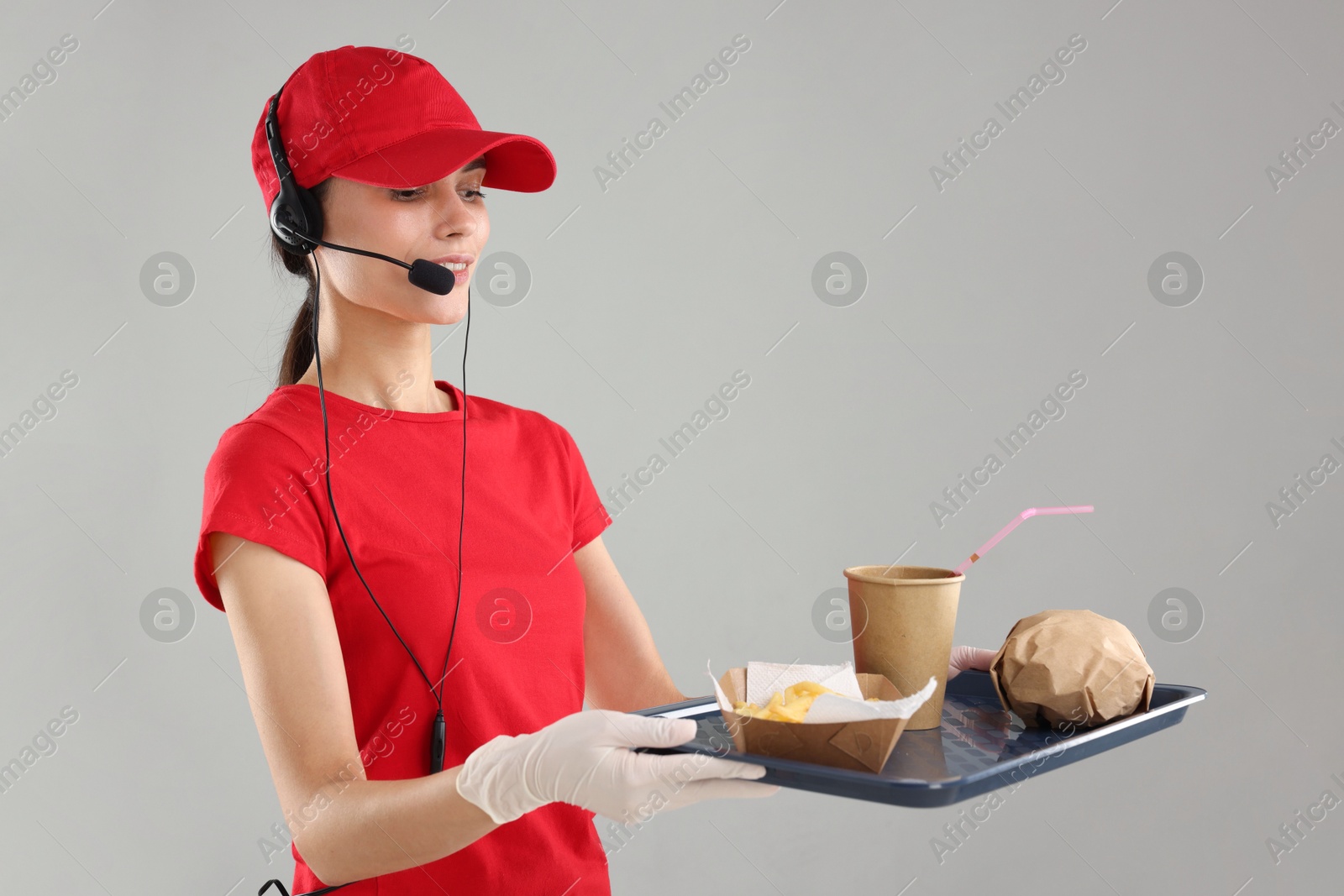 Photo of Fast-food worker holding tray with order on gray background,