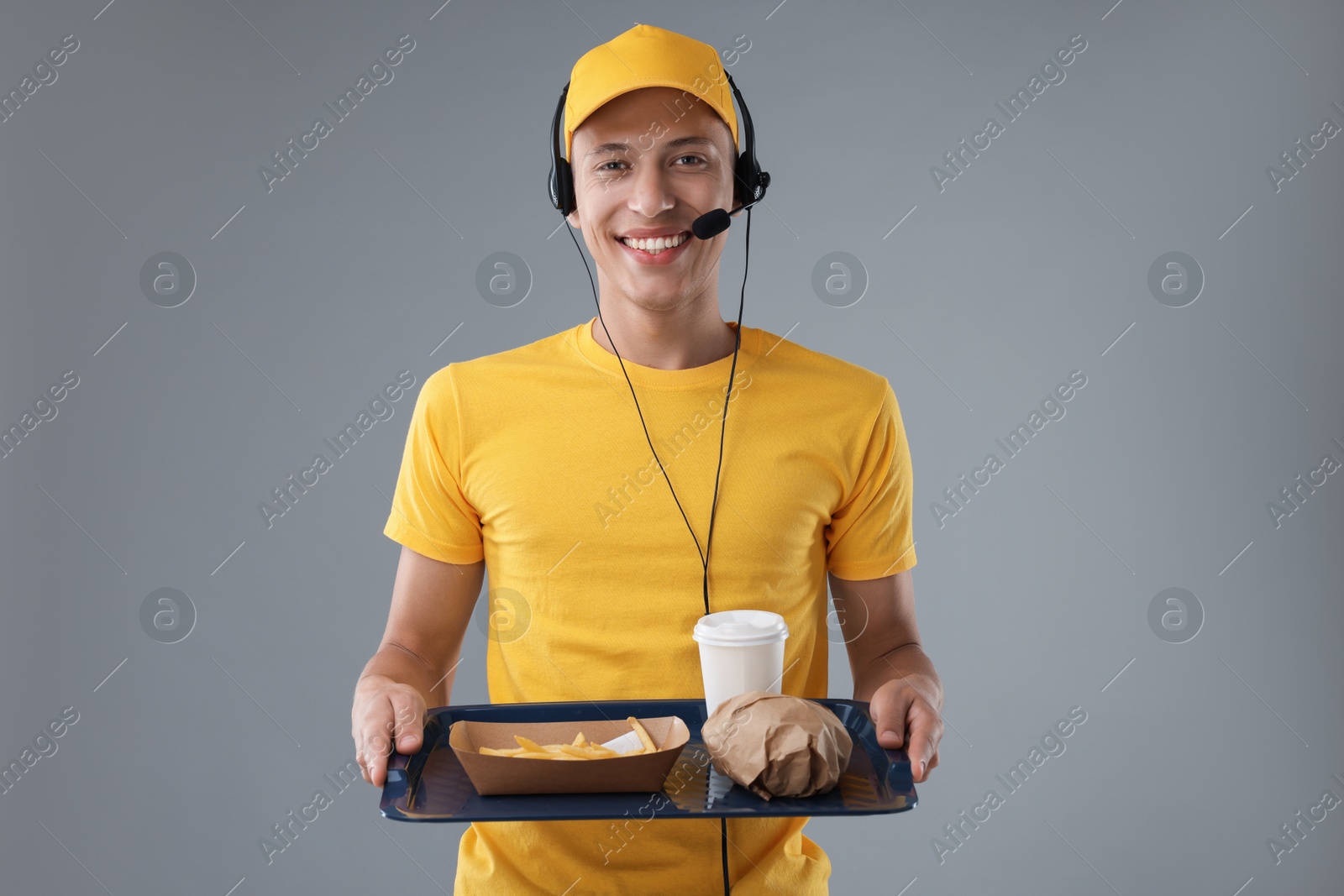 Photo of Fast-food worker holding tray with order on gray background