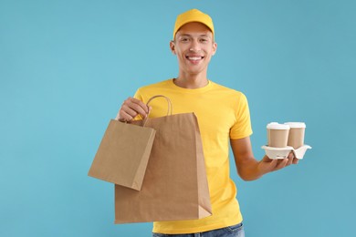 Photo of Fast-food worker with paper bags and cups on light blue background