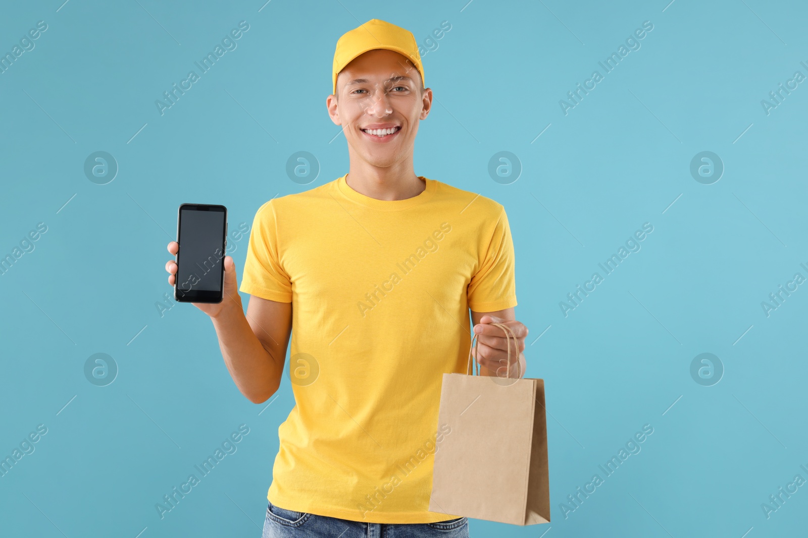 Photo of Fast-food worker with paper bag and smartphone on light blue background