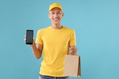 Photo of Fast-food worker with paper bag and smartphone on light blue background