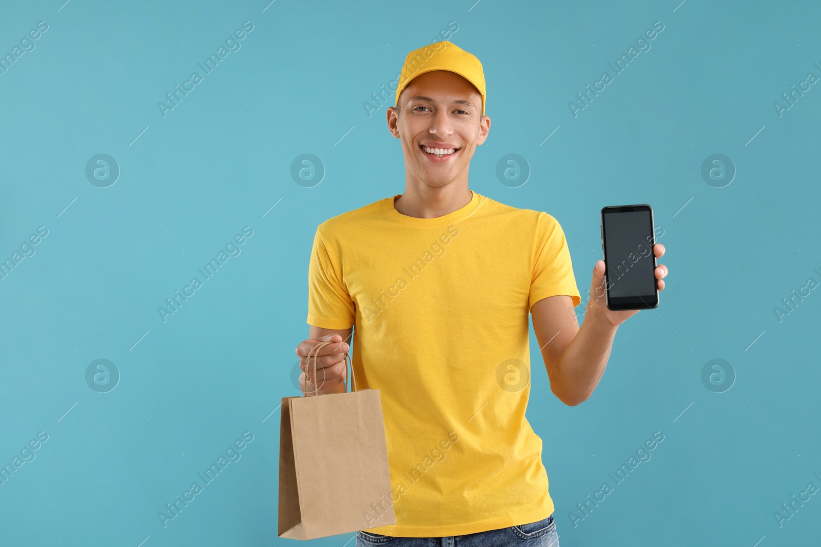 Photo of Fast-food worker with paper bag and smartphone on light blue background