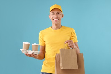 Photo of Fast-food worker with paper bags and cups on light blue background