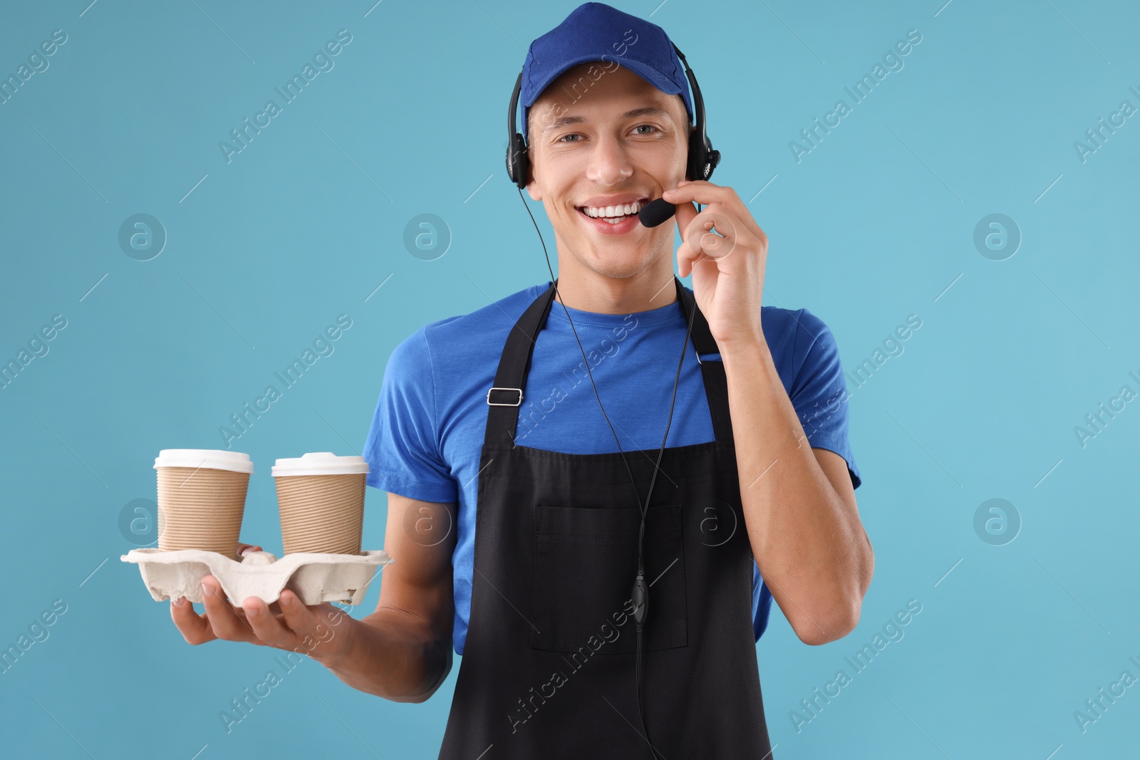 Photo of Fast-food worker with paper cups on light blue background