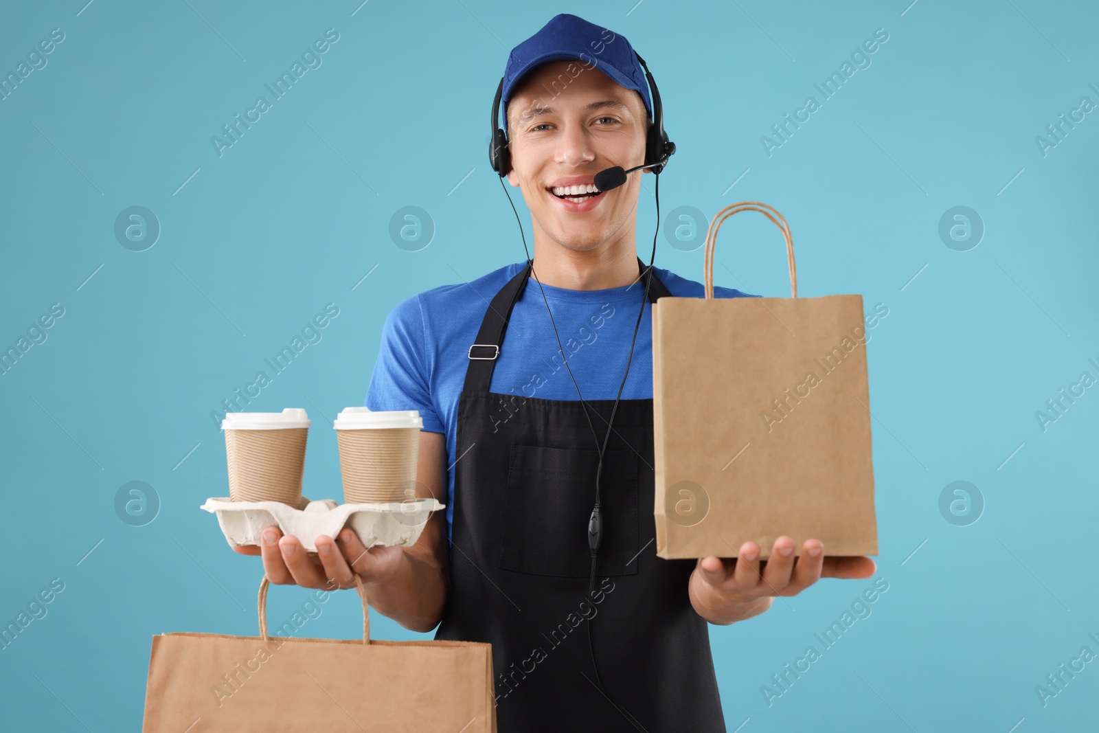 Photo of Fast-food worker with paper bags and cups on light blue background