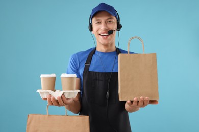 Photo of Fast-food worker with paper bags and cups on light blue background