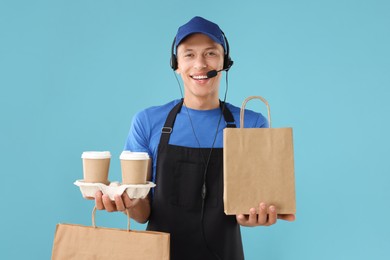 Photo of Fast-food worker with paper bags and cups on light blue background