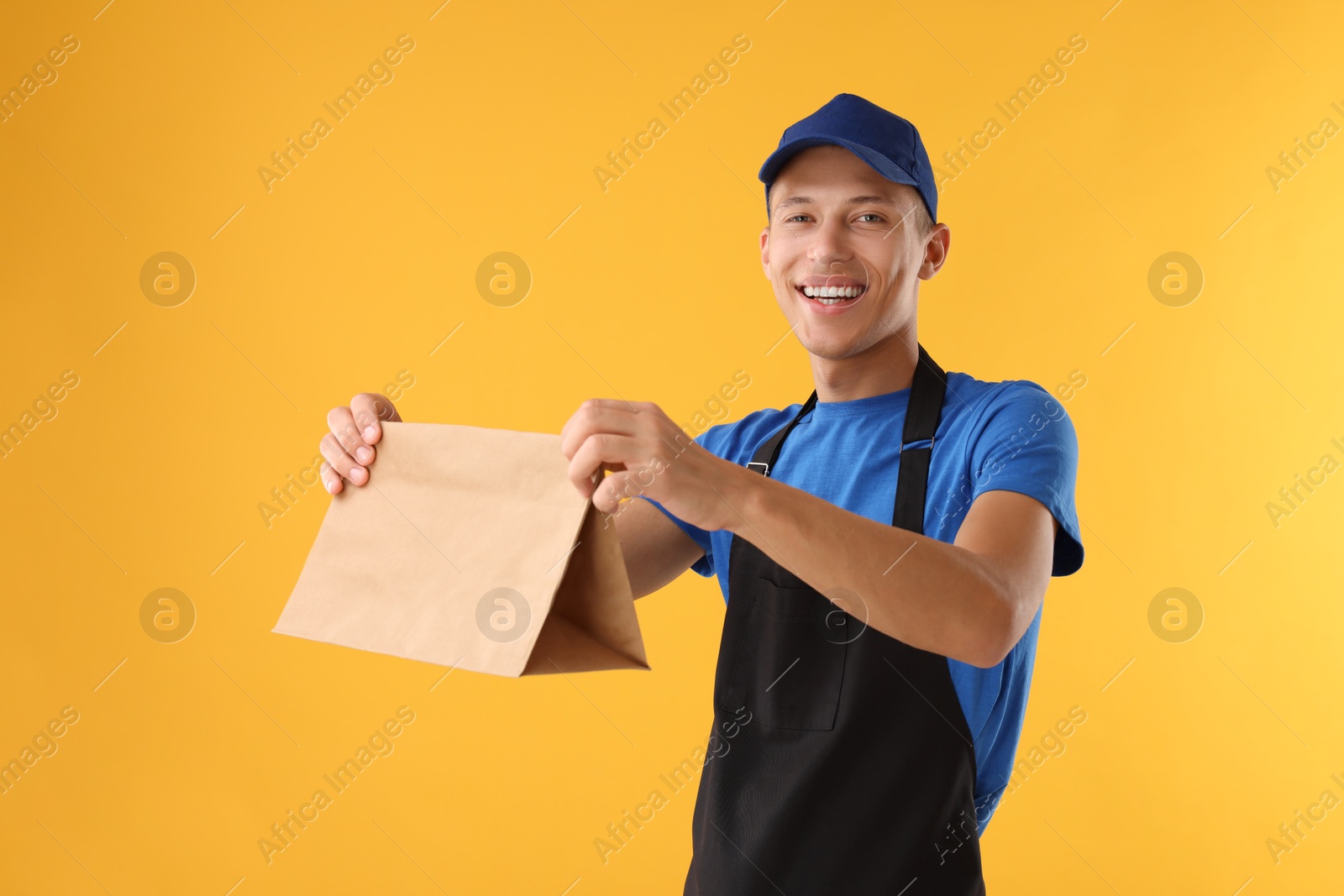 Photo of Fast-food worker with paper bag on orange background