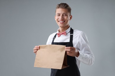 Photo of Fast-food worker with paper bag on gray background