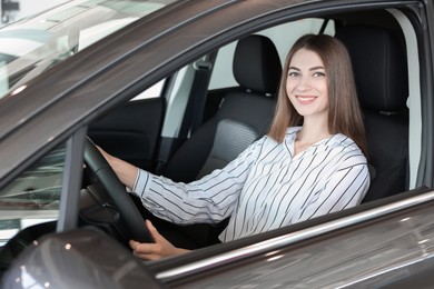 Photo of Happy young woman inside new car in salon