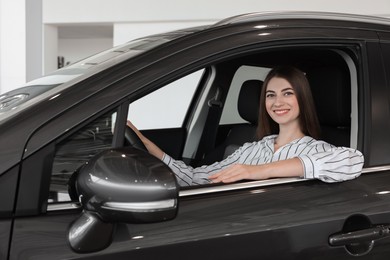 Photo of Happy young woman inside new car in salon