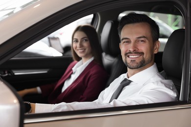 Happy saleswoman and client inside new car in salon