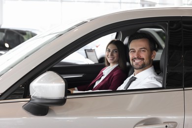 Happy saleswoman and client inside new car in salon