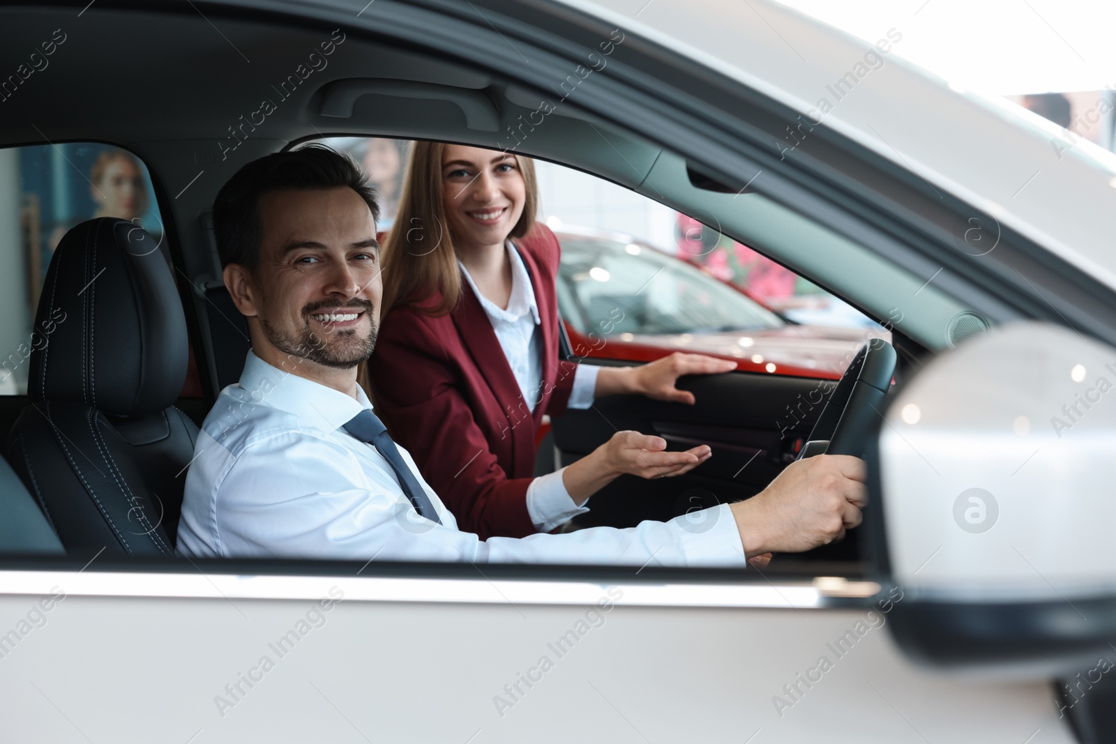 Photo of Happy saleswoman and client inside new car in salon