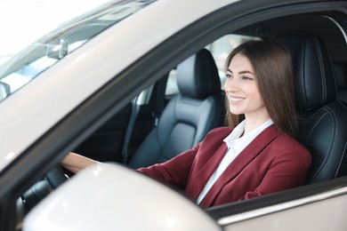 Photo of Young woman inside new car in salon